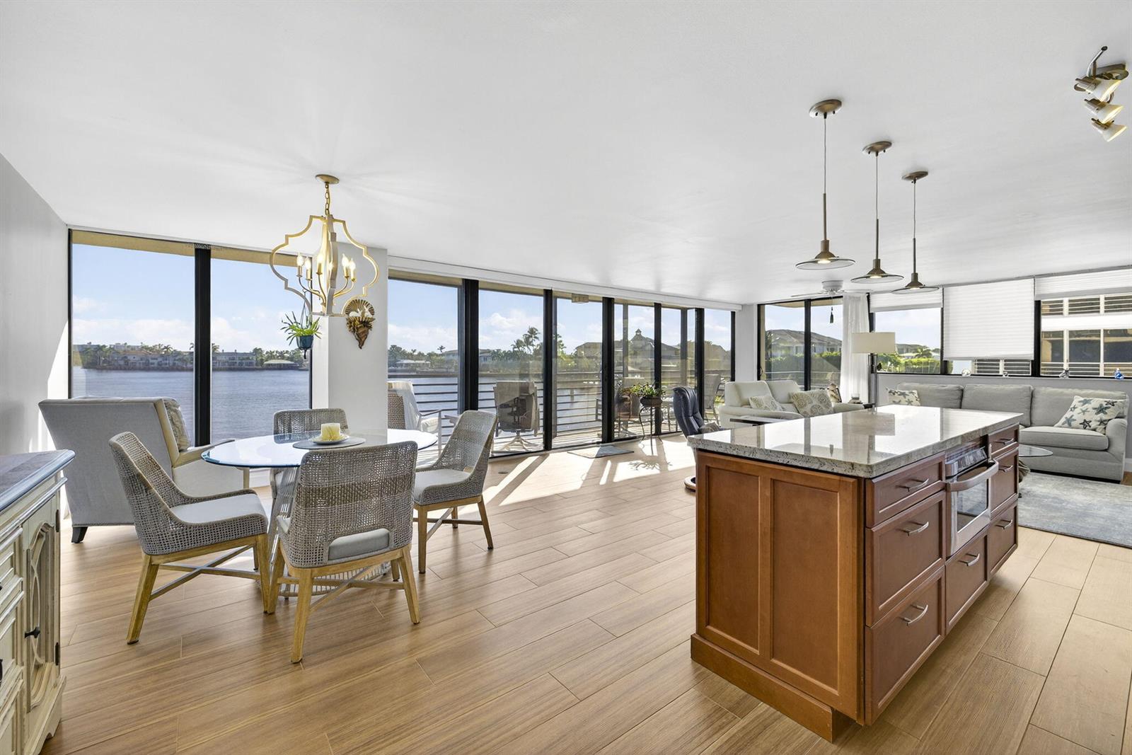 An open-concept living and dining area features wood-look tile flooring and floor-to-ceiling waterfront windows — 900 NE Spanish River Boulevard # 2w, Boca Raton FL 33431, BOCA RATON, FL