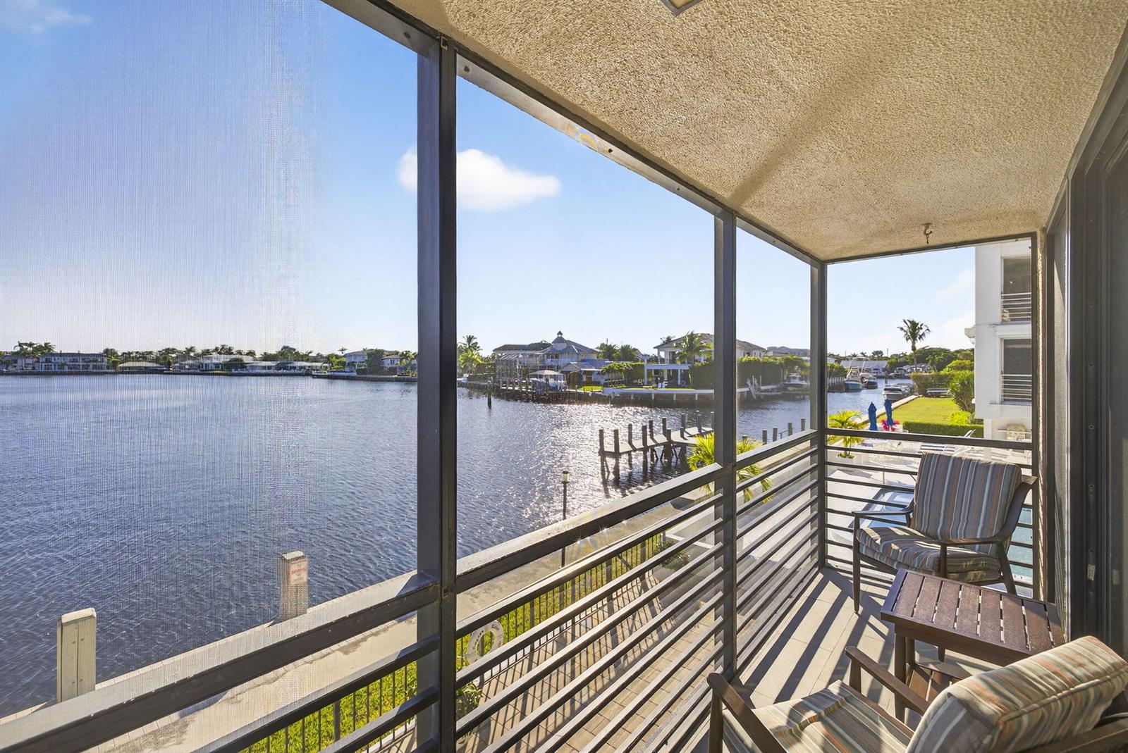 A screened-in balcony overlooks a canal with docks and waterfront homes — 900 NE Spanish River Boulevard # 2w, Boca Raton FL 33431, BOCA RATON, FL