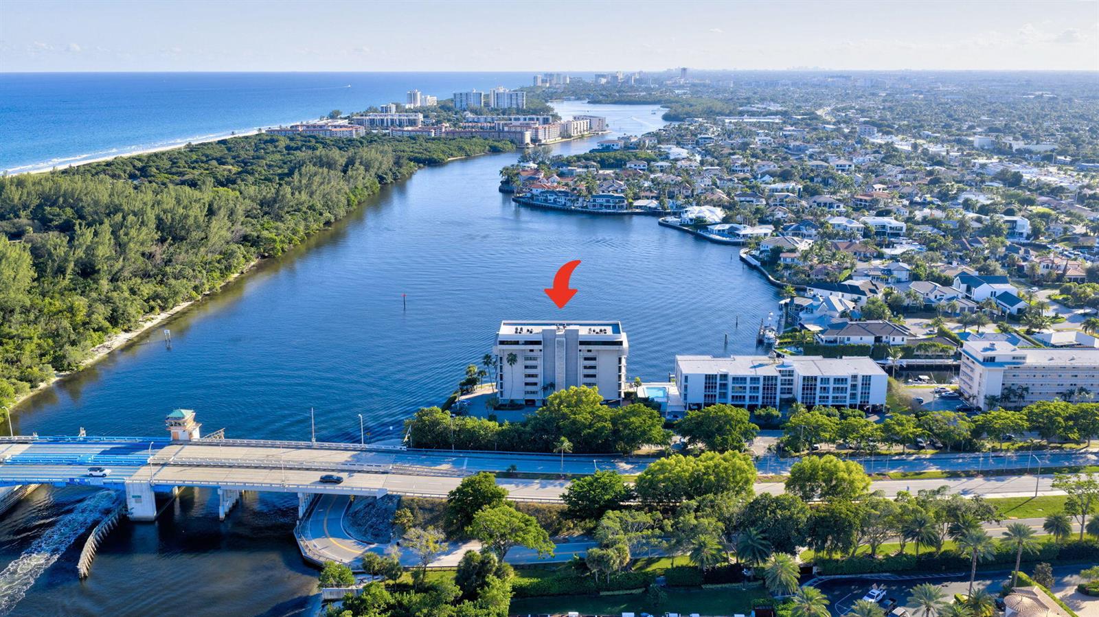 An aerial view shows a multi-story apartment building situated on a waterfront point near a bridge — 900 NE Spanish River Boulevard # 2w, Boca Raton FL 33431, BOCA RATON, FL