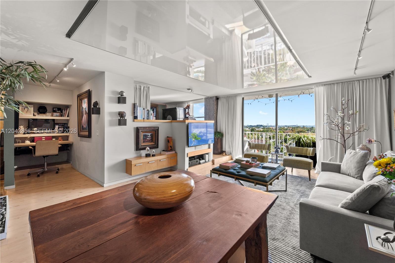 A living room with a wooden table, grey sofa, office nook, and balcony with city views — 2350 NE 135th St # 808, North Miami FL 33181, NORTH MIAMI, FL