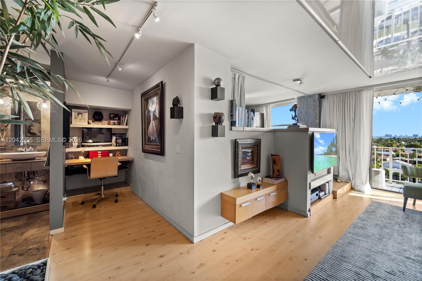 A modern living area features a built-in desk, a television partition, and a balcony view — 2350 NE 135th St # 808, North Miami FL 33181, NORTH MIAMI, FL