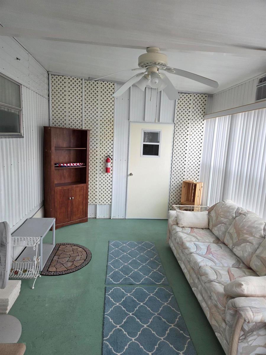 A sunroom features a ceiling fan, a floral sofa, blue rugs, and lattice wall panels — 2915 Roger Street, Sebring FL 33872, SEBRING, FL