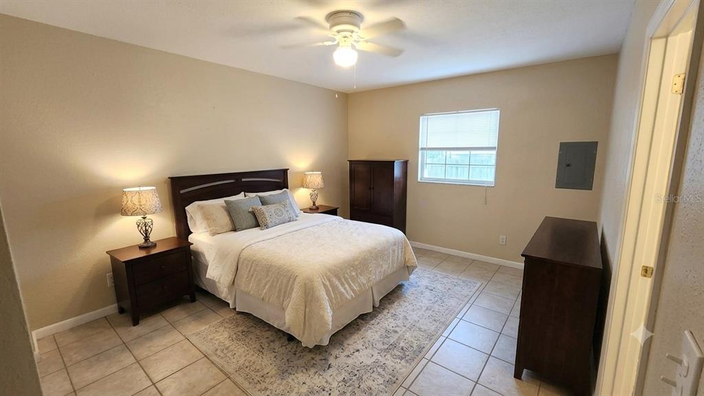 A bedroom features a bed with a patterned rug, tile flooring, and a ceiling fan — 716 21ST STREET N, ST PETERSBURG, FL