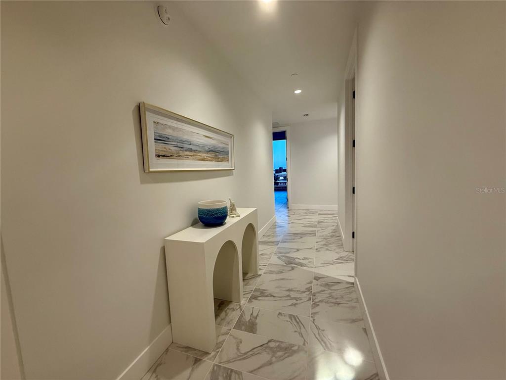 A hallway features white walls, marble-patterned tile flooring, and a white arched console table — 777 3RD AVENUE N UNIT 908, ST PETERSBURG, FL