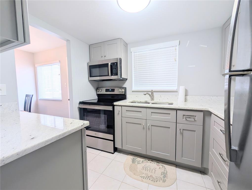 A kitchen features gray cabinets, stainless steel appliances, and light-colored granite countertops — 2008 CANAL DRIVE UNIT M3, BRADENTON, FL