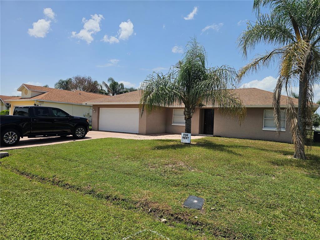 A single-story house with a tan exterior, a two-car garage, and a front yard — 102 WHITEHALL WAY, KISSIMMEE, FL