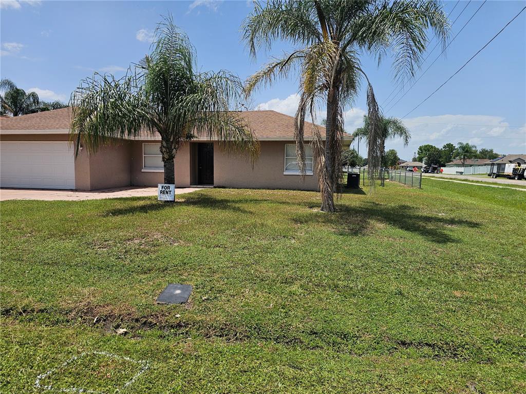A single-story tan house with a two-car garage and palm trees in the front yard — 102 WHITEHALL WAY, KISSIMMEE, FL