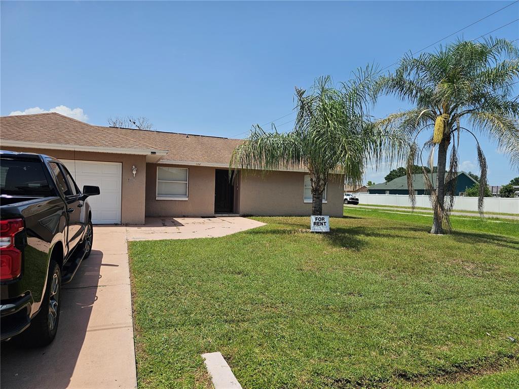 A single-story house with a tan exterior, a garage, and a palm tree in the yard — 102 WHITEHALL WAY, KISSIMMEE, FL