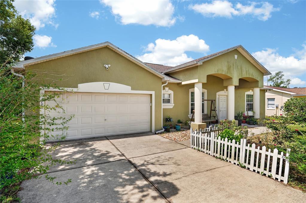 A single-story house with a two-car garage, stucco exterior, and a white picket fence — 2728 SW 153RD PLACE ROAD, OCALA, FL