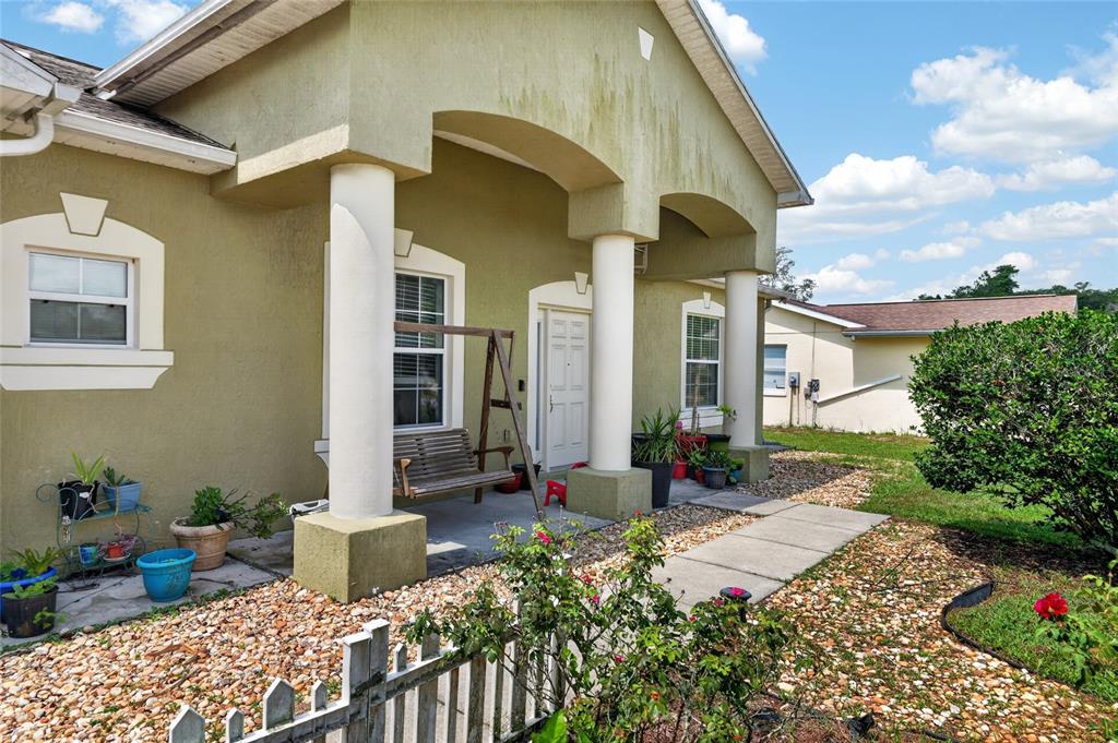 The exterior of a house features a covered porch with white columns and a swing — 2728 SW 153RD PLACE ROAD, OCALA, FL