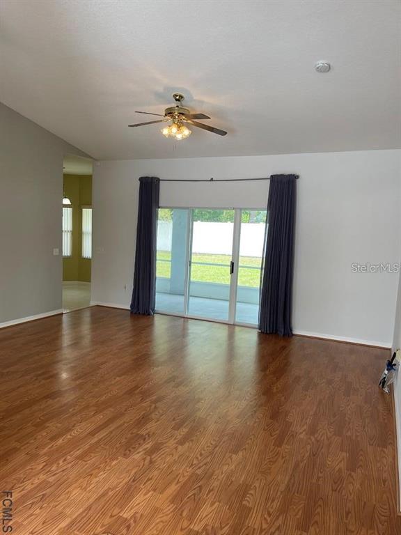 A living room with wood-look flooring, a ceiling fan, and sliding glass doors to a patio — 13 FREEMONT TURN, PALM COAST, FL