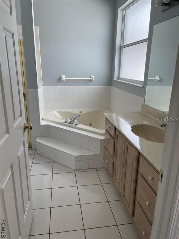 A bathroom features a corner soaking tub, a tiled floor, and a wooden vanity cabinet — 13 FREEMONT TURN, PALM COAST, FL