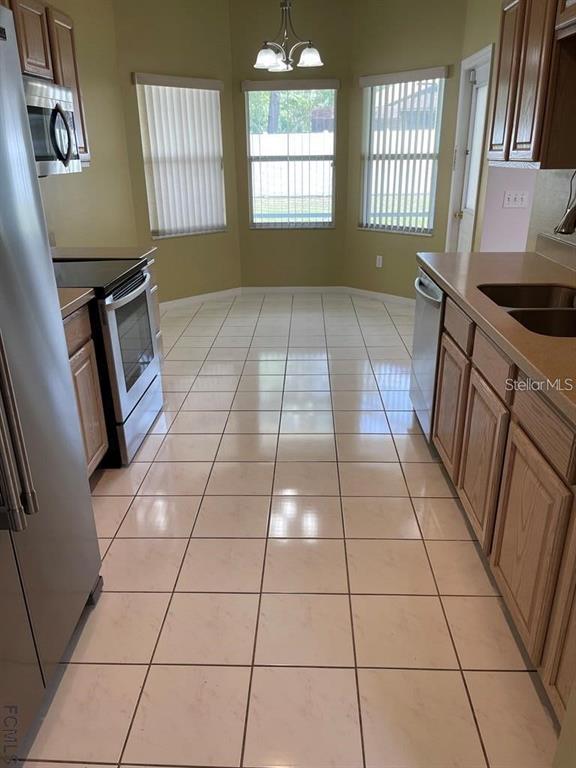 A kitchen features light wood cabinets, stainless steel appliances, tile flooring, and a breakfast nook — 13 FREEMONT TURN, PALM COAST, FL