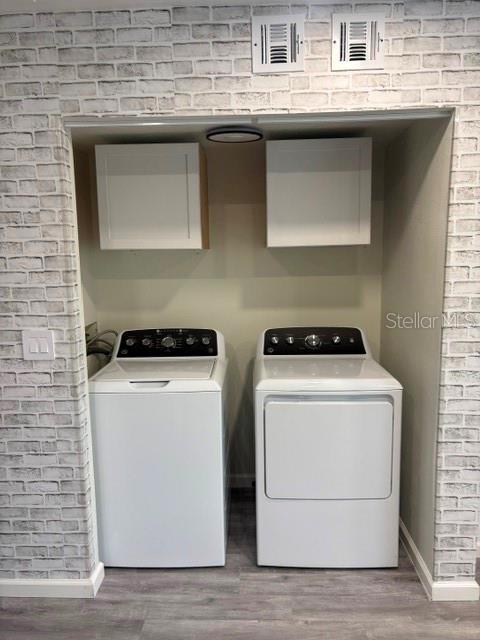 A laundry area features a white washer and dryer set beneath two wall-mounted cabinets — 3204 BRIGADOON DRIVE, CLEARWATER, FL