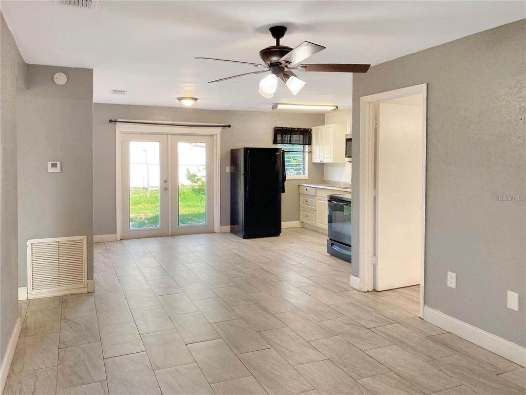 A kitchen and dining area with tile flooring, a black refrigerator, and glass patio doors — 49 ORANGE PARK BOULEVARD, LAKE WALES, FL