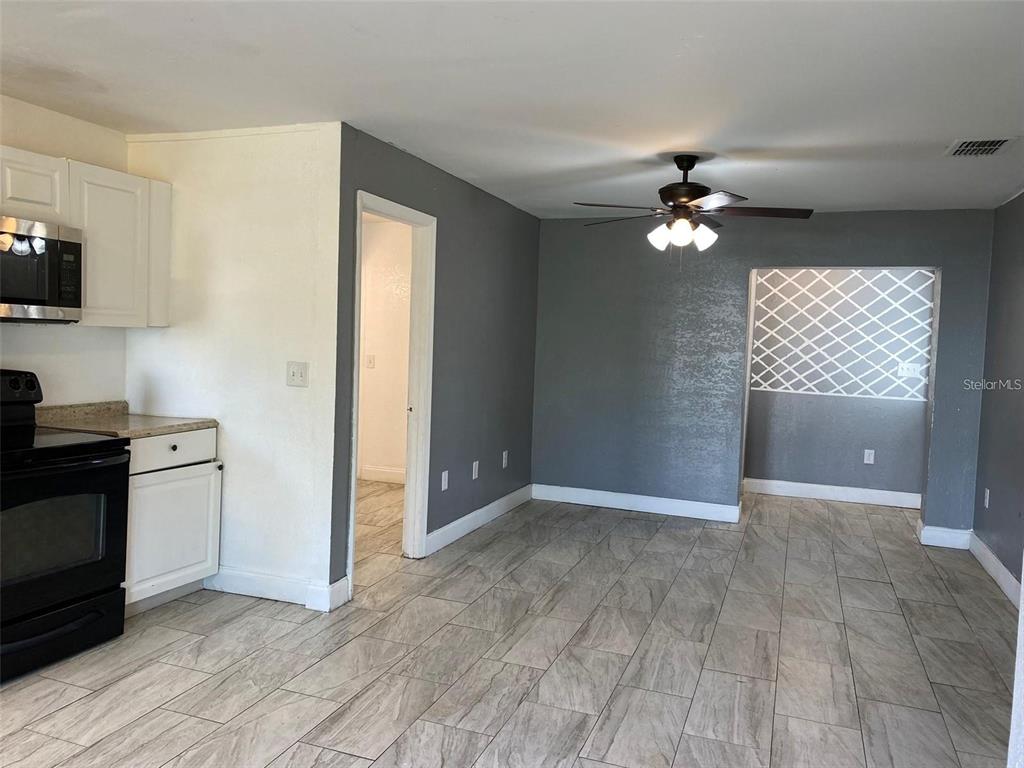 A kitchen and dining area feature white cabinets, gray walls, and light-colored wood-look tile flooring — 49 ORANGE PARK BOULEVARD, LAKE WALES, FL