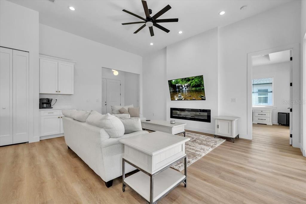A living room features a white sofa, a fireplace with a mounted television, and light flooring — 3083 JEANNIN DRIVE, NORTH PORT, FL