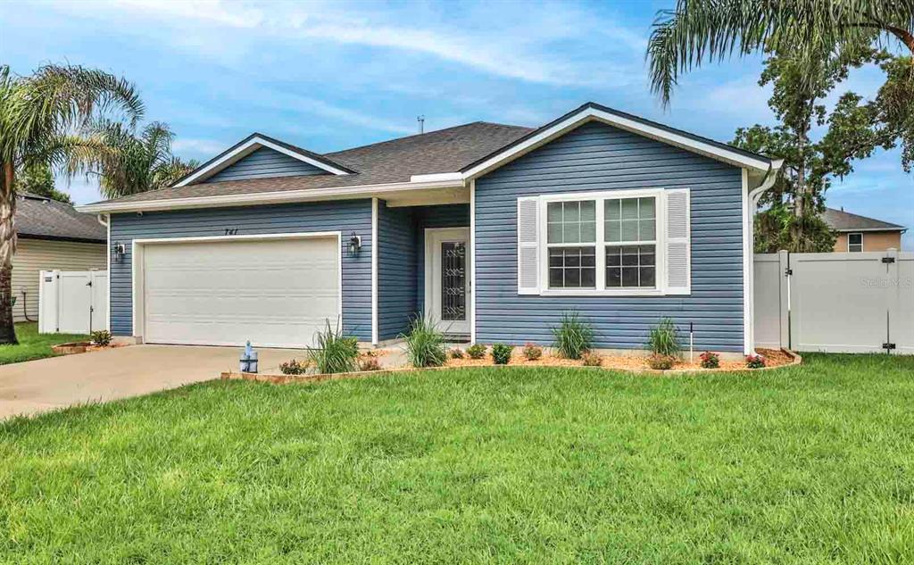 A blue single-story house with a two-car garage, white shutters, and a front lawn — 741 MYSTIC OAKS LANE, DELAND, FL