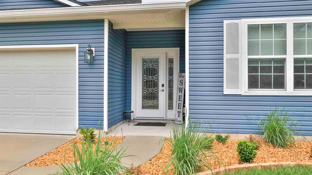 The exterior of a blue-sided house features a white front door and a garage — 741 MYSTIC OAKS LANE, DELAND, FL