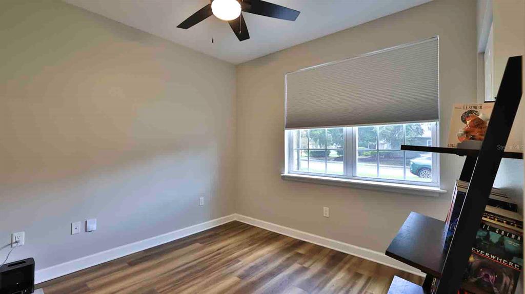 An empty bedroom features light-colored walls, wood-look flooring, a ceiling fan, and a window — 741 MYSTIC OAKS LANE, DELAND, FL
