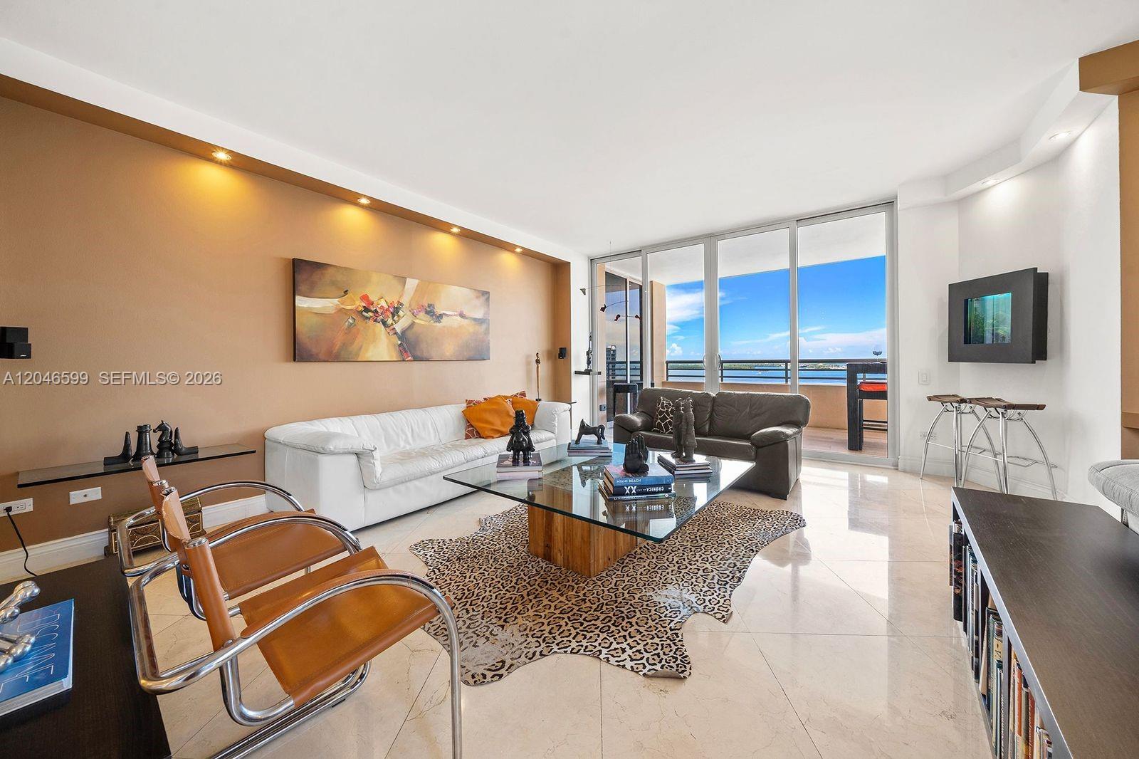 A living room features a glass coffee table, animal print rug, and balcony with water views — 808 Brickell Key Dr # 1808, Miami FL 33131, MIAMI, FL
