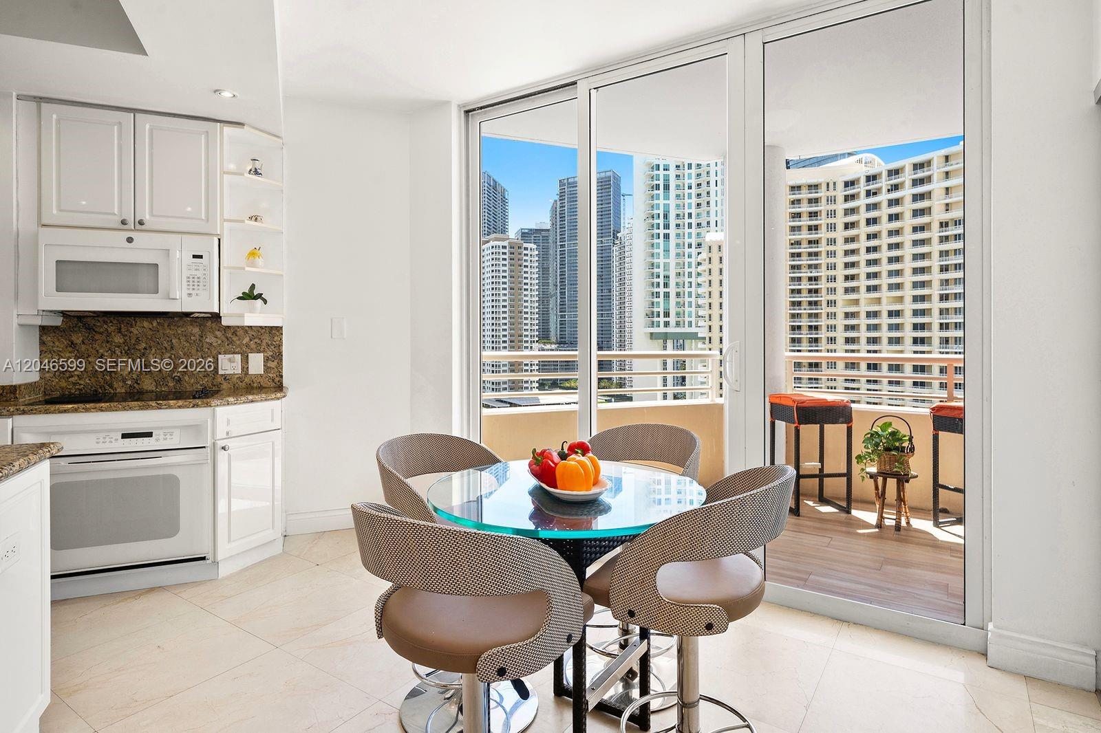 A kitchen and dining area feature a glass table, modern chairs, and a balcony view — 808 Brickell Key Dr # 1808, Miami FL 33131, MIAMI, FL