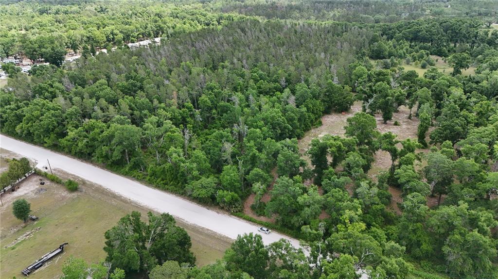 An aerial view shows a paved road running alongside a wooded lot with cleared areas — 0 SUNTILT COURT, WHITE SPRINGS, FL