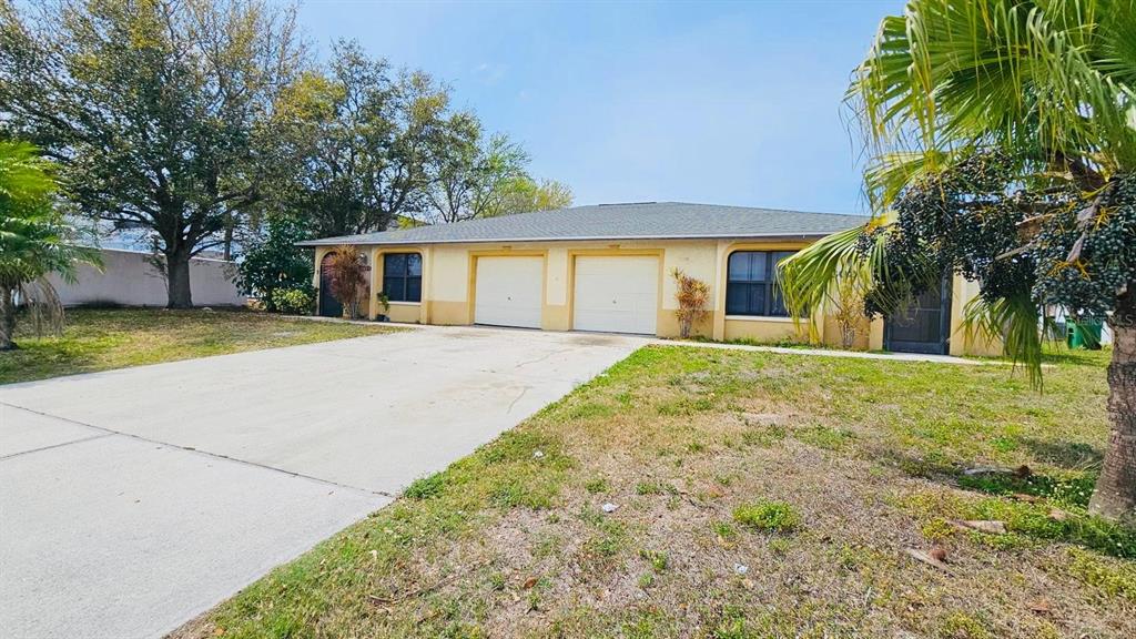 A single-story duplex with two garage doors and a concrete driveway under a clear sky — 3026 SANTA BARBARA BOULEVARD, CAPE CORAL, FL