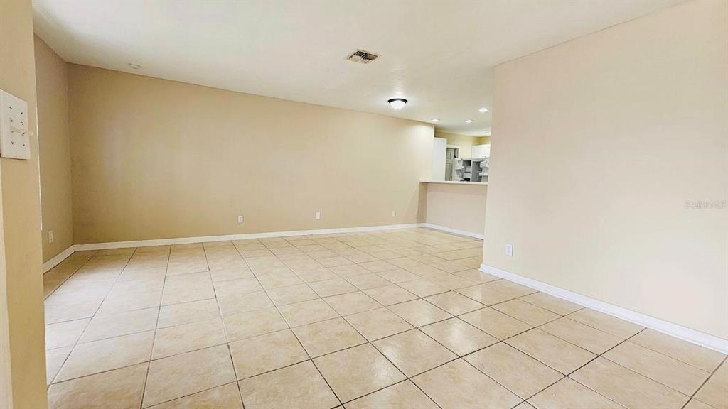 An empty room with beige walls and light-colored tile flooring features a breakfast bar — 3026 SANTA BARBARA BOULEVARD, CAPE CORAL, FL