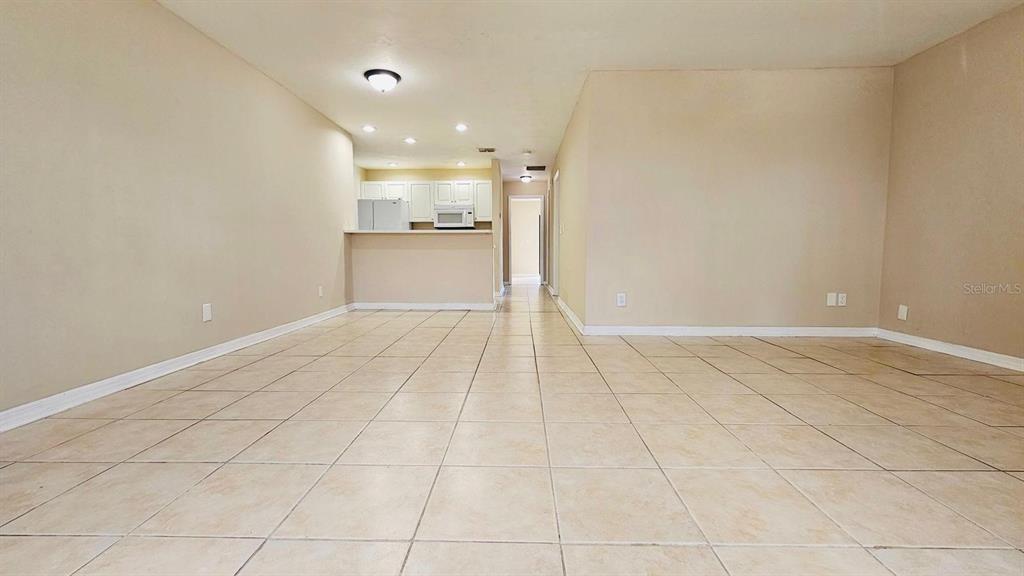 An open-concept living area features light-colored tile flooring and a view into the kitchen — 3026 SANTA BARBARA BOULEVARD, CAPE CORAL, FL