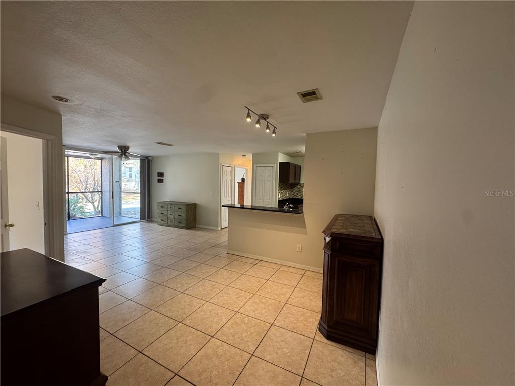 An open-concept living area features tiled floors, a breakfast bar, and a screened-in patio — 7605 PISSARRO DRIVE UNIT 13108, ORLANDO, FL