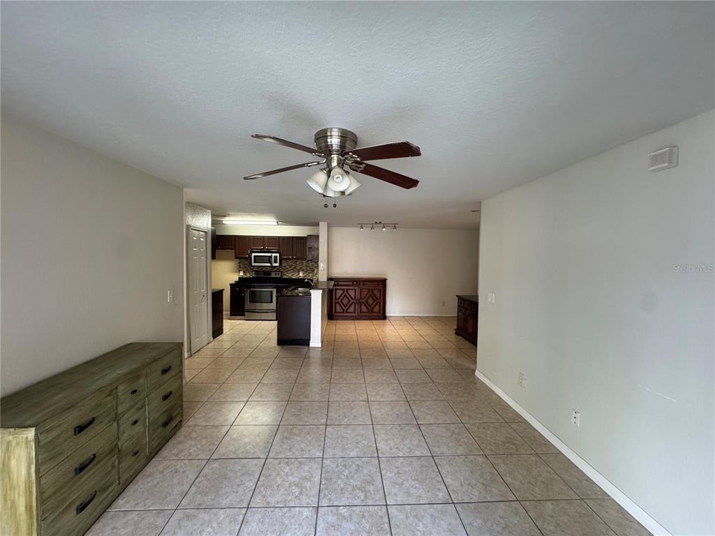 An open-concept living and dining area features tile flooring, a ceiling fan, and a kitchen — 7605 PISSARRO DRIVE UNIT 13108, ORLANDO, FL