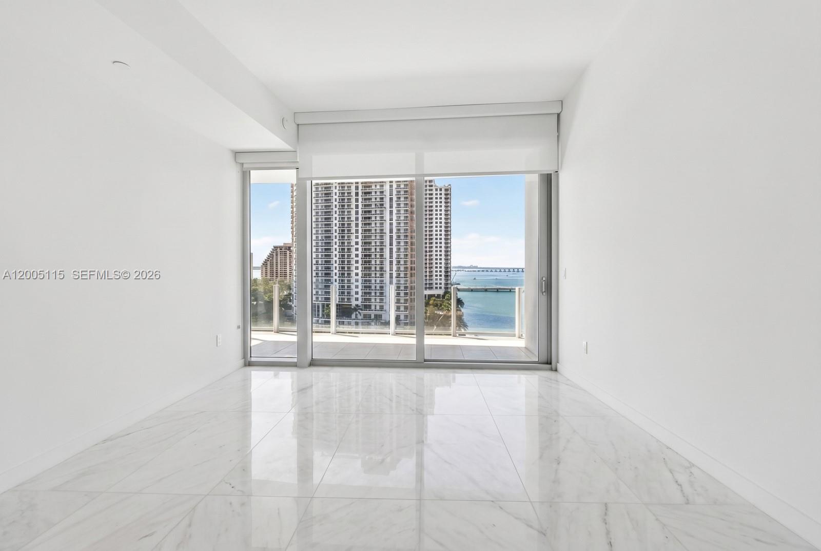 An empty room with white walls, marble flooring, and a sliding glass door to a balcony — 300 Biscayne Blvd Way # 1002, Miami FL 33131, MIAMI, FL