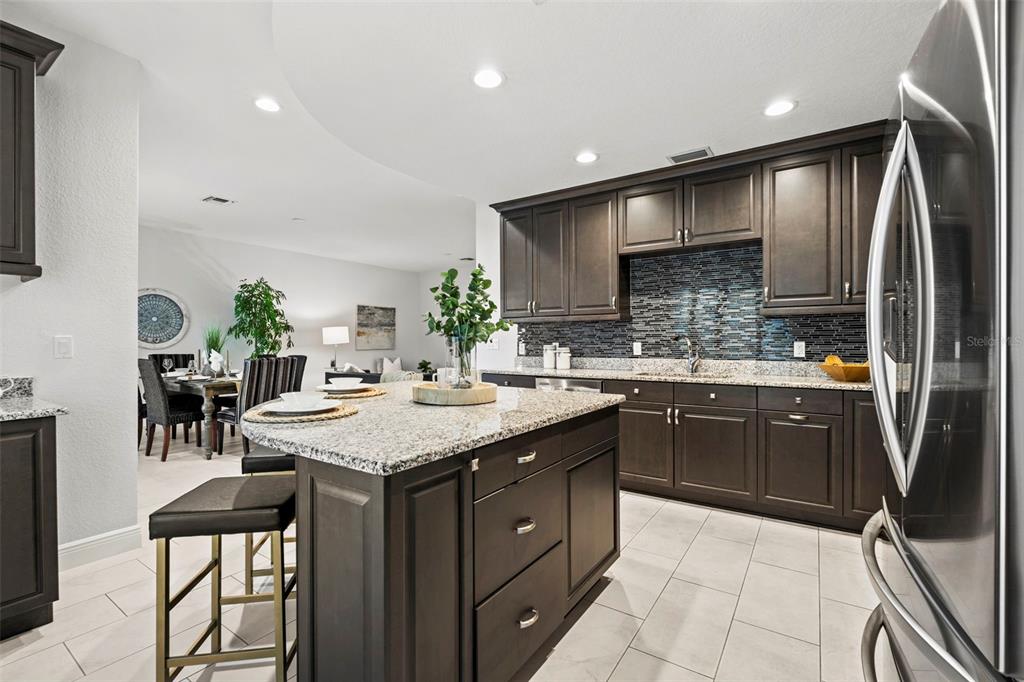 A kitchen with dark wood cabinets, granite countertops, a center island, and tile flooring — 771 DATE PALM LANE, ST PETERSBURG, FL