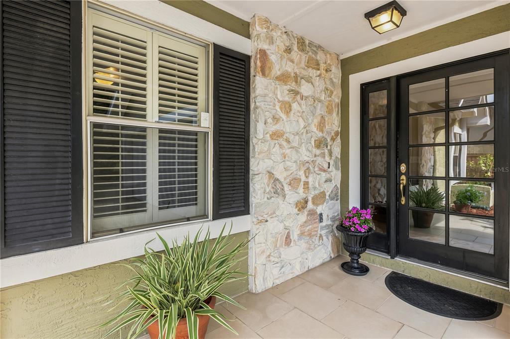 A front porch features a stone accent wall, a black-framed glass door, and a potted plant — 3200 HEATHGATE COURT, ORLANDO, FL