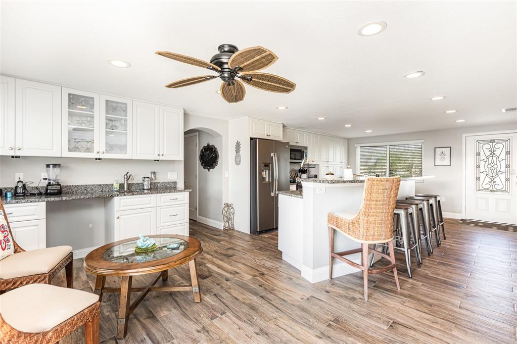 A kitchen and living area featuring white cabinets, granite countertops, and wood-look tile flooring — 3811 101ST STREET W, BRADENTON, FL