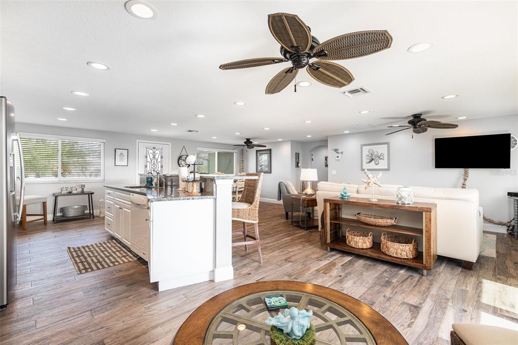 An open-concept kitchen and living area features wood-look tile flooring and a ceiling fan — 3811 101ST STREET W, BRADENTON, FL