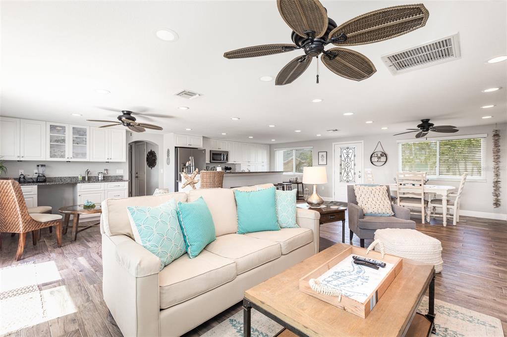 An open-concept living room and kitchen featuring light-colored cabinetry, a beige sofa, and ceiling fans — 3811 101ST STREET W, BRADENTON, FL