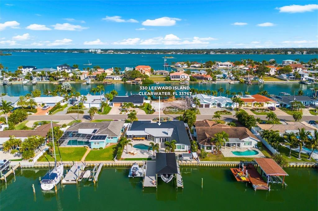 An aerial view of a single-story house with a metal roof and circular driveway at sunset — 330 LEEWARD ISLAND, CLEARWATER BEACH, FL