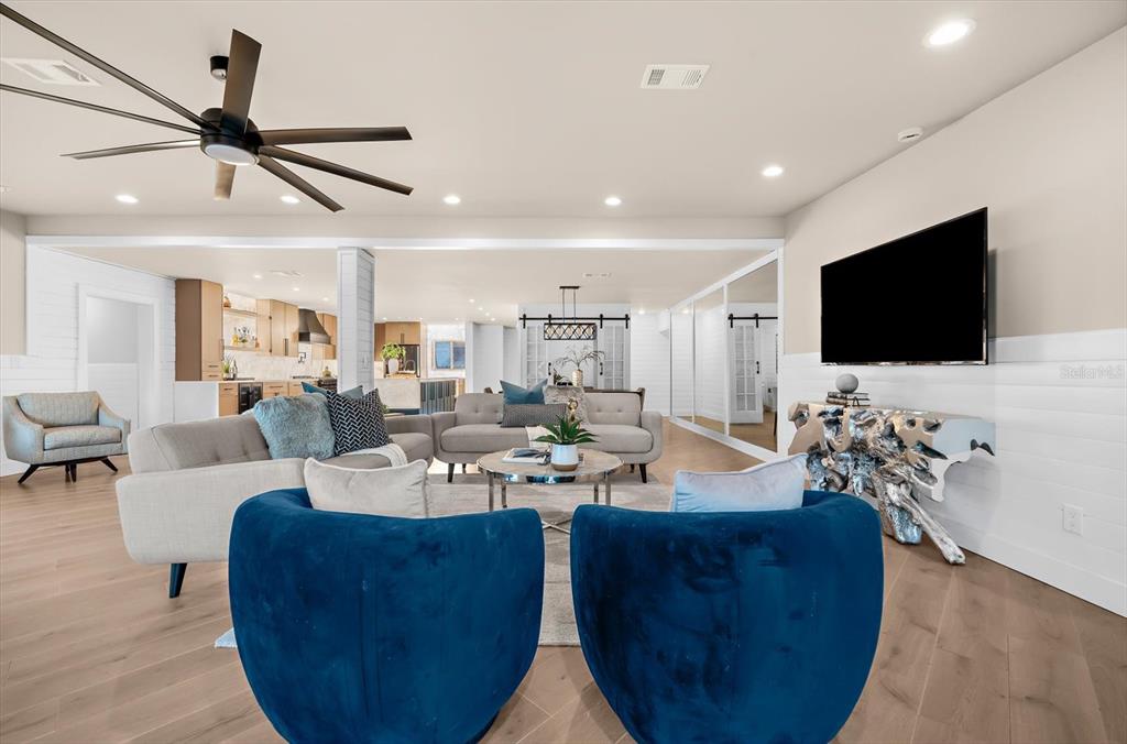 A living room features blue velvet chairs, a grey sofa, and a wall-mounted television — 330 LEEWARD ISLAND, CLEARWATER BEACH, FL