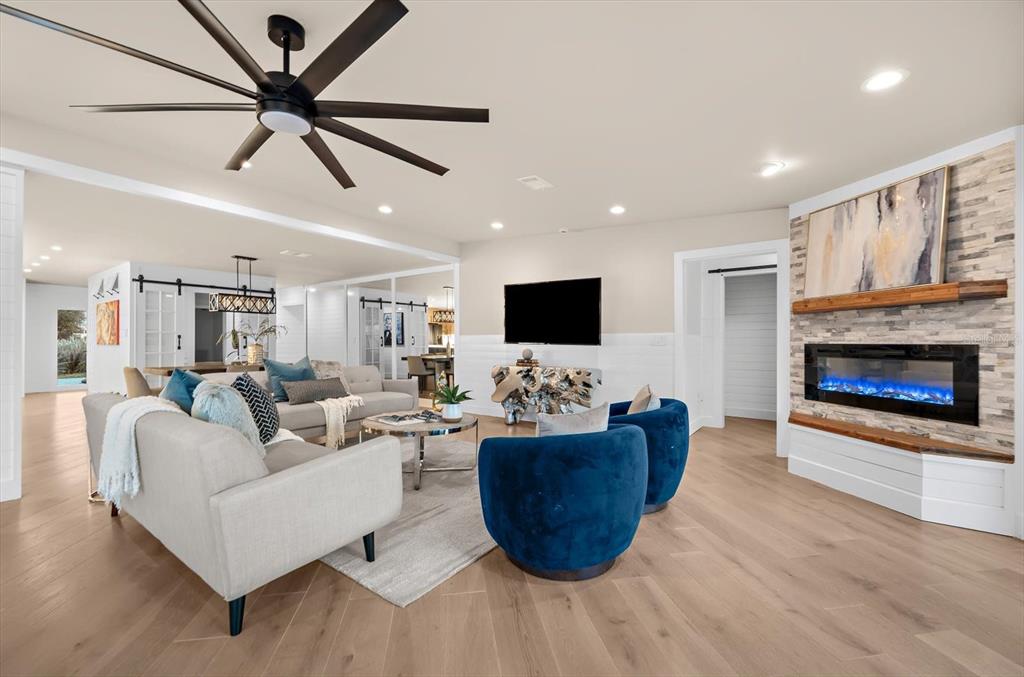 A living room features a stone fireplace, blue armchairs, a gray sofa, and a ceiling fan — 330 LEEWARD ISLAND, CLEARWATER BEACH, FL