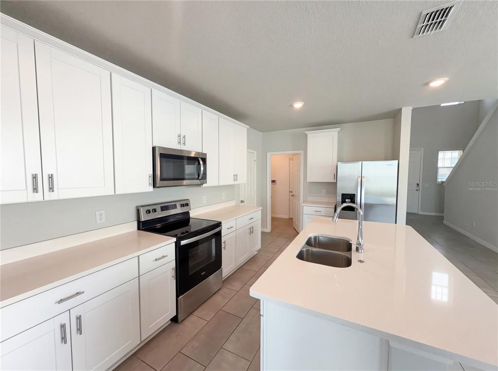 A kitchen with white cabinets, stainless steel appliances, and a central island with a sink — 3092 BELLA VISTA DRIVE, DAVENPORT, FL