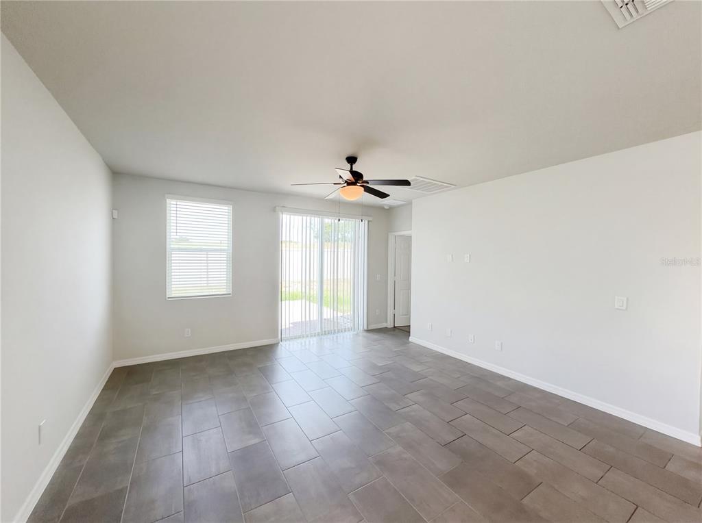 A living room features gray tile flooring, a ceiling fan, and sliding glass patio doors — 3092 BELLA VISTA DRIVE, DAVENPORT, FL