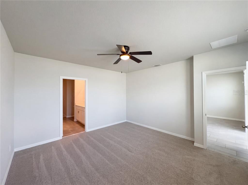 A carpeted bedroom features a ceiling fan, two doorways, and neutral-colored walls — 3092 BELLA VISTA DRIVE, DAVENPORT, FL