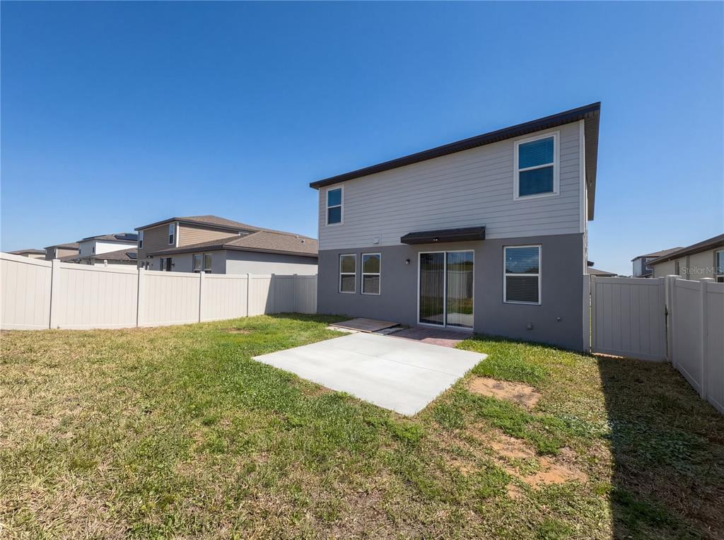 The backyard features a concrete patio, a white vinyl fence, and a two-story house — 3092 BELLA VISTA DRIVE, DAVENPORT, FL