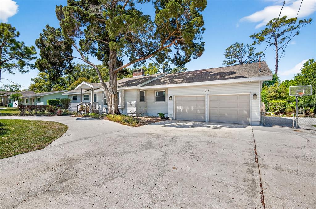 A single-story house with light siding, a two-car garage, and a large front yard tree — 1520 S KEENE ROAD, CLEARWATER, FL