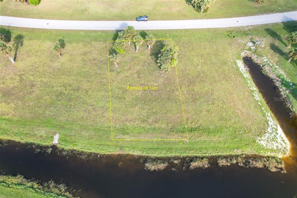 An aerial view shows a rectangular vacant lot outlined in yellow next to a canal — 16208 SAN EDMUNDO ROAD, PUNTA GORDA, FL
