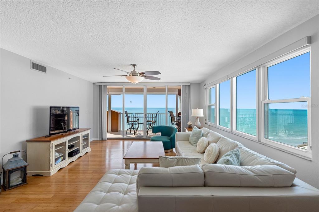 A living room with a white sofa, wood floors, and a balcony overlooking the ocean — 16326 GULF BOULEVARD UNIT 510, REDINGTON BEACH, FL