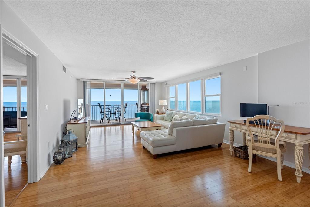 A living room with hardwood floors, a white sectional sofa, and a balcony overlooking water — 16326 GULF BOULEVARD UNIT 510, REDINGTON BEACH, FL