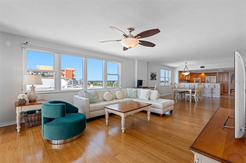 A living room with hardwood floors, a white sectional sofa, and a teal accent chair — 16326 GULF BOULEVARD UNIT 510, REDINGTON BEACH, FL